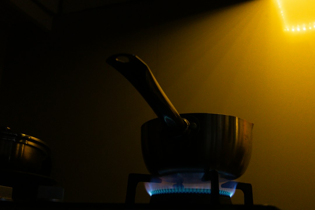 A warm kitchen scene showing cast iron skillet seasoning in progress on a stovetop with a faint sheen of oil